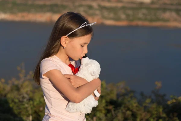 Child girl is embracing soft toy bear. — Stock Photo, Image