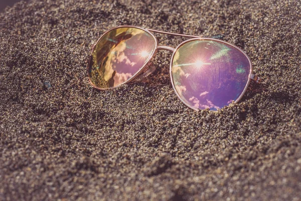 Sluneční brýle na pláži s oblohou a sluncem reflexe. — Stock fotografie
