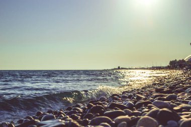 Gün batımında kumsalda çakıl taşları. Batan güneşin ışınlarında bulanık arkaplan