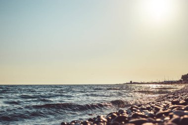 Gün batımında kumsalda çakıl taşları. Batan güneşin ışınlarında bulanık arkaplan