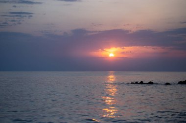 Gün batımında kumsalda çakıl taşları. Batan güneşin ışınlarında bulanık arkaplan