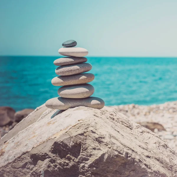 Steinpyramide auf Sand symbolisiert Zen, Harmonie, Gleichgewicht. Ozean bei Sonnenuntergang im Hintergrund — Stockfoto