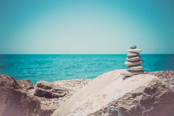 Kamienna piramida na piasku symbolizująca zen, harmonię, równowagę. Ocean o zachodzie słońca w tle — Zdjęcie stockowe