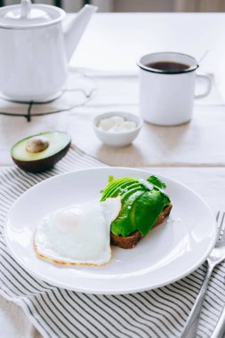 Sağlıklı avokado tost, kahve ve beyaz masa üzerinde yumurta. Düz yatıyordu, önden görünüm.