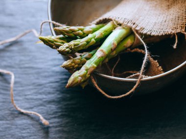 Bir avuç siyah mazisi üzerinde taze yeşil kuşkonmaz