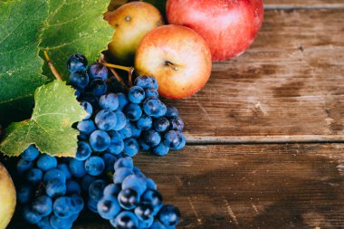 Elma, üzüm ve üzüm ile sonbahar arka plan eski ahşap arka plan üzerinde bırakır. Sonbaharda hasat.