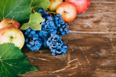 Elma, üzüm ve üzüm ile sonbahar arka plan eski ahşap arka plan üzerinde bırakır. Sonbaharda hasat.