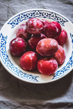 Erik bir desen ile beyaz bir seramik tabak içinde farklı çeşitleri. Gri beton arka plan, gri Tekstil peçete. Üstten görünüm. Bahçe, tarım, hasat kavramı.