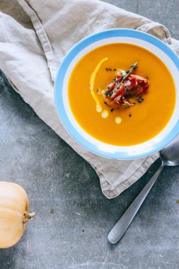 Gri arka plan üzerine balkabağı çorbası tabak