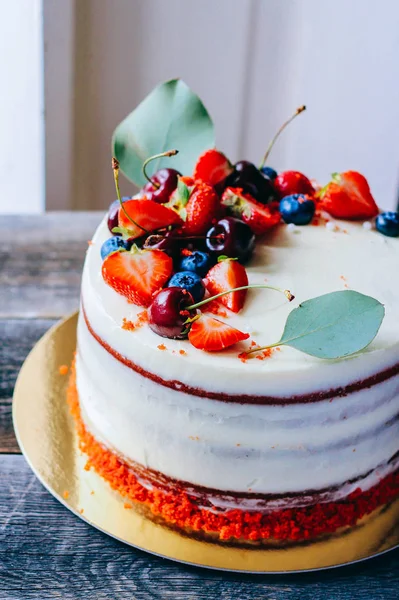 Kırmızı kadife kek çilek, yaban mersini, kiraz ve okaliptüs ahşap arka plan üzerinde yapılan berry dekorasyonu ile