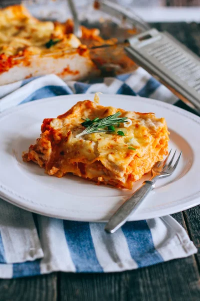 Beyaz bir tabakta servis edilen kişniş yapraklı kıymalı bolonez soslu geleneksel lazanya.