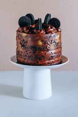 Surgut, Rusya - Nisan 2016: Altın pullu bukleler ve bisküvi Oreo beyaz pasta stand süslenmiş ile çikolatalı kek