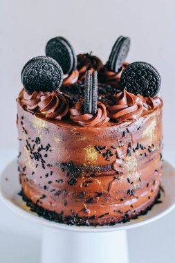 Surgut, Rusya - Nisan 2016: Altın pullu bukleler ve bisküvi Oreo beyaz pasta stand süslenmiş ile çikolatalı kek