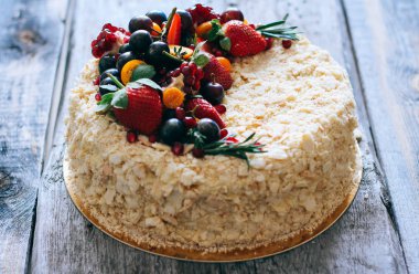 Çilek, üzüm, yaban mersini ve physalis ahşap zemin ile dekore kek Napoleon