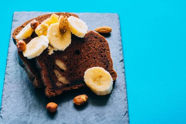 Çikolatalı muzlu ekmek muz ve mavi arka plan günü kahvaltıda fındık ile siyah mazisi üzerinde.