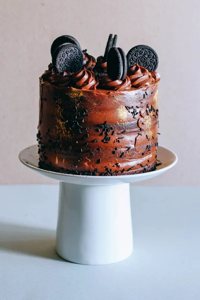 Surgut, Rusya - Nisan 2016: Altın pullu bukleler ve bisküvi Oreo beyaz pasta stand süslenmiş ile çikolatalı kek