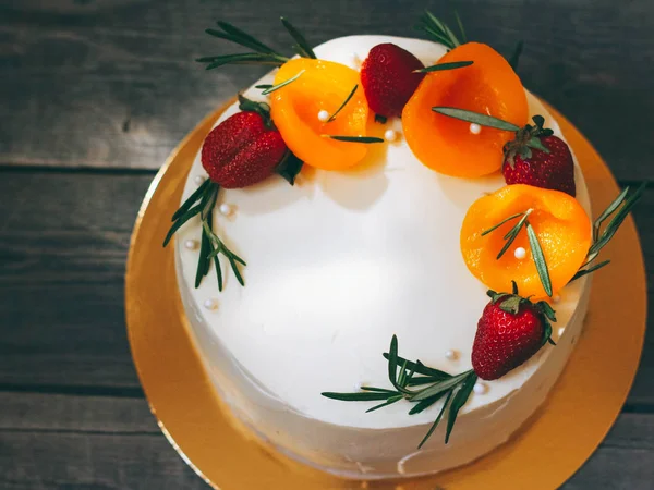 Doğum günü pastası ile tereyağı krema, çilek, şeftali ve eski bir ahşap zemin üzerine biberiye ile dekore edilmiştir. Üstten görünüm