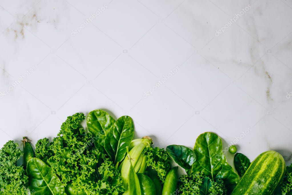 Frame of fresh green vegetables on a marble background, copy space, flay lay, top view