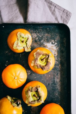 Trabzon hurması ve mandalina mermer bir zemin üzerine siyah tepsisinde