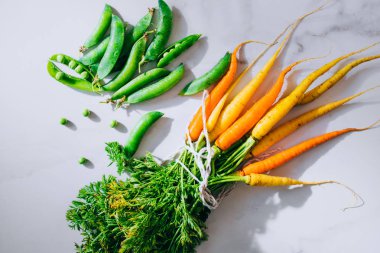 Taze kirli sebze havuç ve bezelye mermer zemin, düz yatıyordu, en iyi görünümü üzerine kökleri
