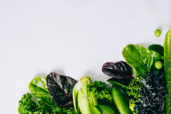 Frame of fresh green vegetables on a marble background, copy space, flay lay, top view