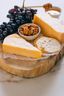 Çedar peyniri, üzüm, fındık, bal ve kırık mermer üzerinde ahşap Pansiyon