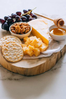 Çedar peyniri, üzüm, fındık, bal ve kırık mermer üzerinde ahşap Pansiyon