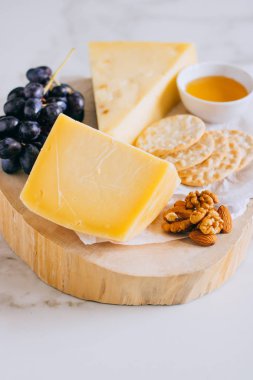 Gruyere peynir, üzüm, fındık, bal ve kırık mermer üzerinde ahşap Pansiyon