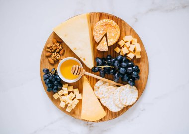 Peynir, üzüm, fındık, bal ve kırık mermer üzerinde ahşap Pansiyon türleri ile düz göklere