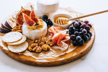 Camembert peyniri, incir, jamon, bal ve üzüm. Mermer zemin üzerine peynir tabağı