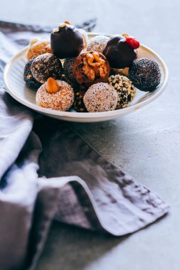 Fındık, incir ve narenciye, trüf gri bir arka plan üzerinde beyaz plaka ile çiğ çikolata şeker. Sağlıklı vegan tatlı.