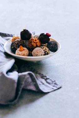 Fındık, incir ve narenciye, trüf gri bir arka plan üzerinde beyaz plaka ile çiğ çikolata şeker. Sağlıklı vegan tatlı.