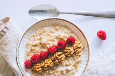 Sabah kahvaltı, yulaf ezmesi süt ile ahududu beyaz bir arka planda üstten görünüm