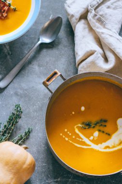 Güveç krem ve kekik gri bir arka planda üstten görünüm ile kabak çorbası