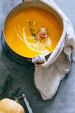 Güveç jambon ve kekik gri bir arka planda üstten görünüm ile kabak çorbası