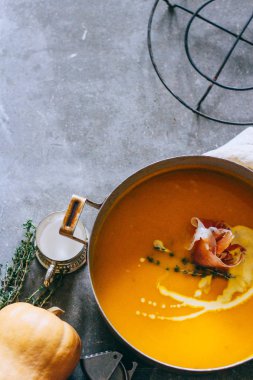 Güveç jambon ve kekik gri bir arka planda üstten görünüm ile kabak çorbası