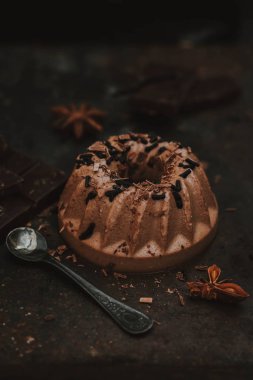 Italian dessert. Panna cotta on dark chocolate, with a chocolate crock and chocolate sprinkles on a dark background clipart