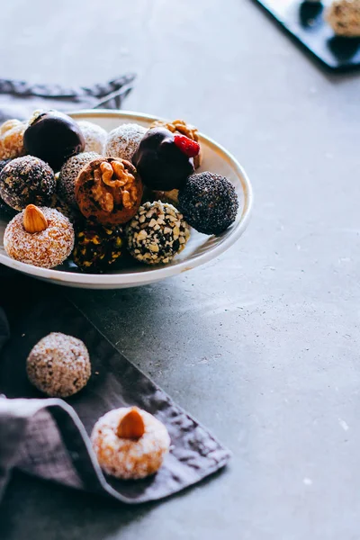 Fındık, incir ve narenciye, trüf gri bir arka plan üzerinde beyaz plaka ile çiğ çikolata şeker. Sağlıklı vegan tatlı.