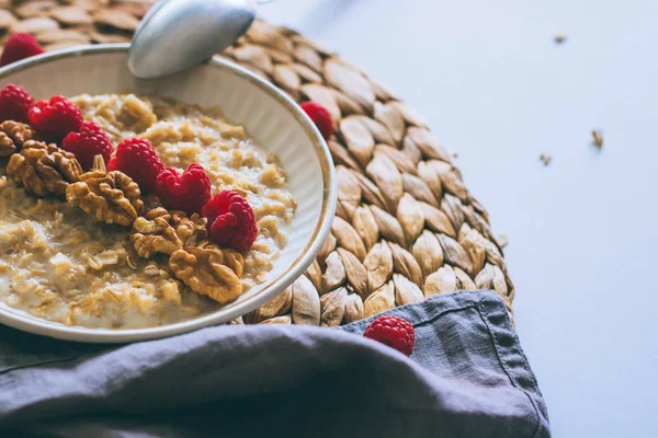 Morning breakfast, oatmeal in milk with raspberries and walnuts