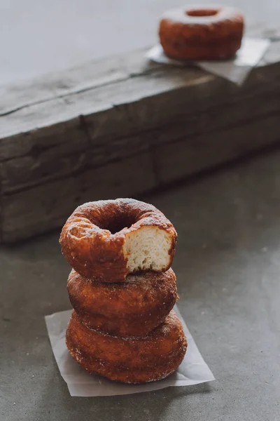 A pile of donuts in powdered sugar. Bite donut.