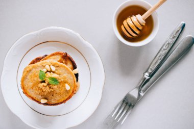 Cevizli, sedir fıstıklı, bal ve nane arkaplanlı muz krepleri bembeyaz arka planda, ballı, üst manzaralı..