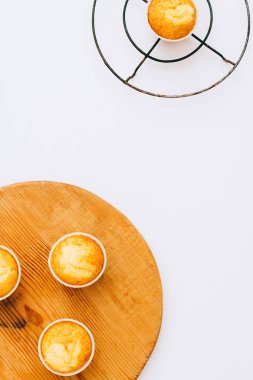 Düz minimalizm ev yapımı turuncu muffins ahşap tahta ve sıcak bir beyaz arka plan, üstten görünüm, kopya alanı altında metal bir stand üzerinde yatıyordu.