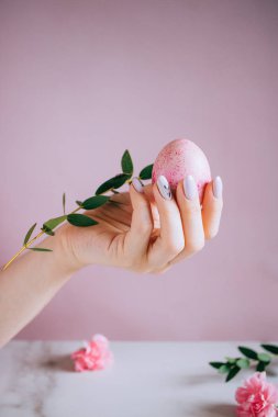Kız elinde tutan pembe bir easter egg, pembe ve mermer arka plan, minimalizm, çiçekler
