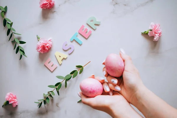 The girl is holding in hand a pink easter egg, pink and marble background, minimalism, flowers