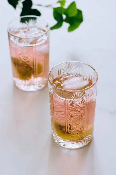 Бокал розового вина в хрустальном бокале на мраморном фоне, зеленый плющ и яркое солнце — стоковое фото