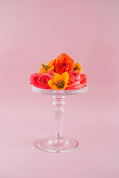 Colorful tropical flowers composition on glass cake stand on pin