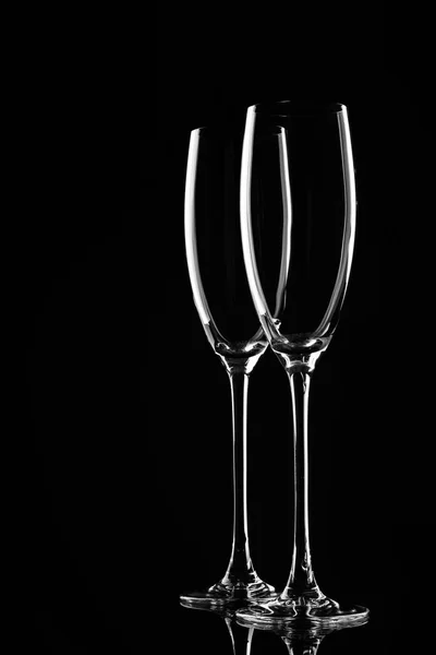 Two empty glasses backlit, on a black background.