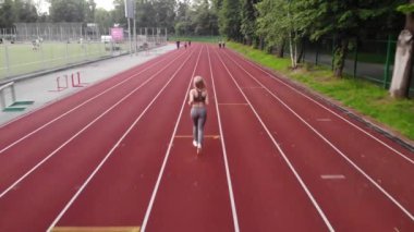 Hava UHD 4k görünümü. Spor parça üzerinde çalışan tarafından spor pratik yapıyor genç atletik kız arka görünümü. Stadyum üzerinden spor kız jogging