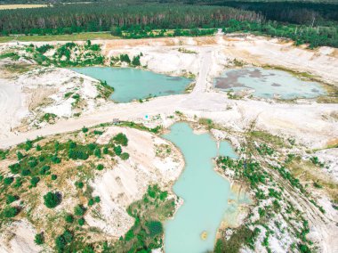 Su basmış bir kaolin ocağında turkuaz su ve beyaz sahille insansız hava aracı görüntüsü. Bir kaolin çukurunun hava incelemesi suyla doldu..