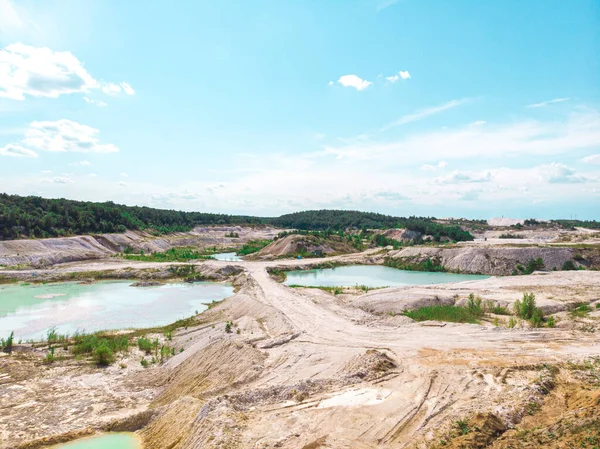 Drone view on a flooded kaolin quarry with turquoise water and white shore. Aerial survey of a kaolin pit flooded with water.